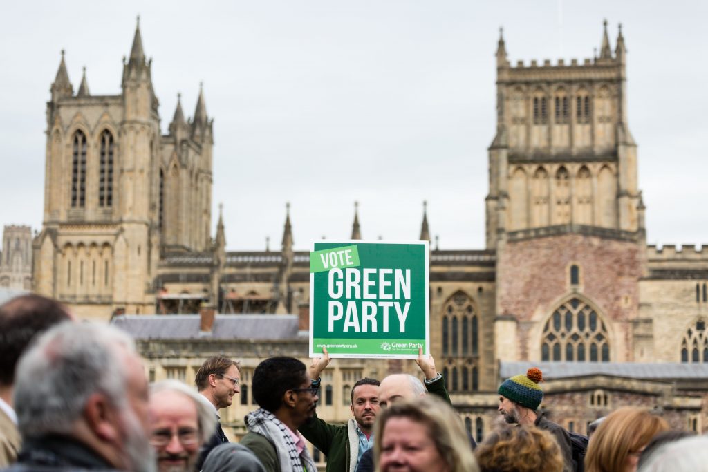 A man holding a 'Vote Green' sign in Bristol