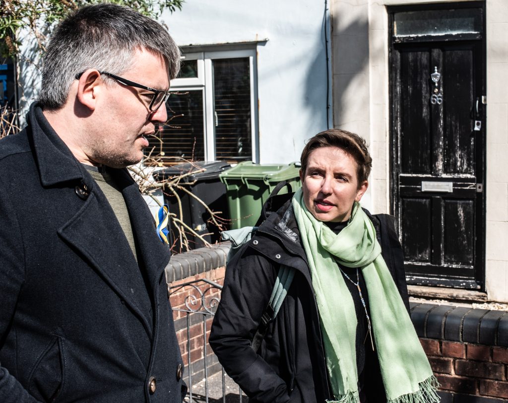 Carla Denyer, MP for Bristol Central, and Cllr Barry Parsons walking in the street outside some houses in conversation
